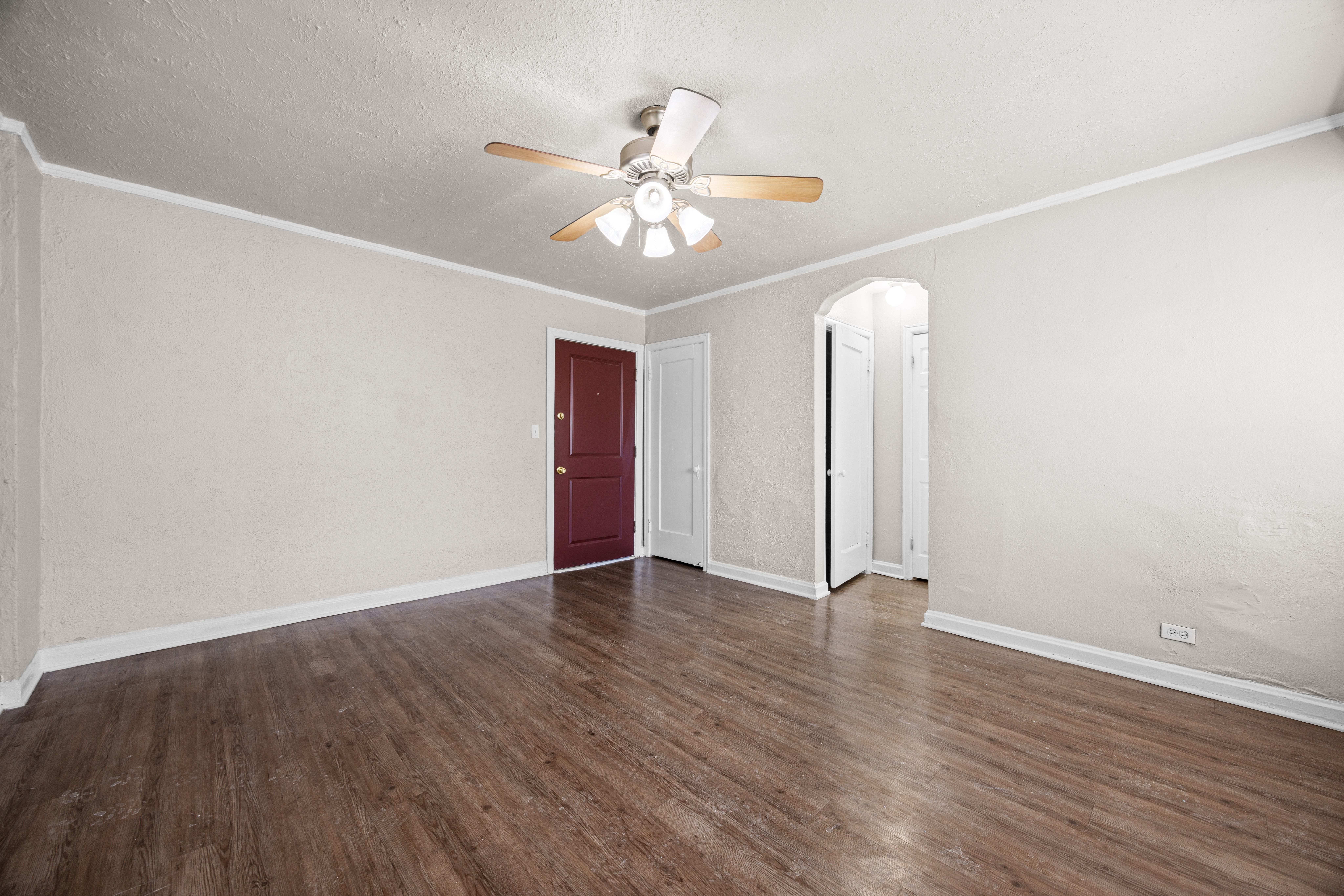 A room with a ceiling fan and wooden flooring.